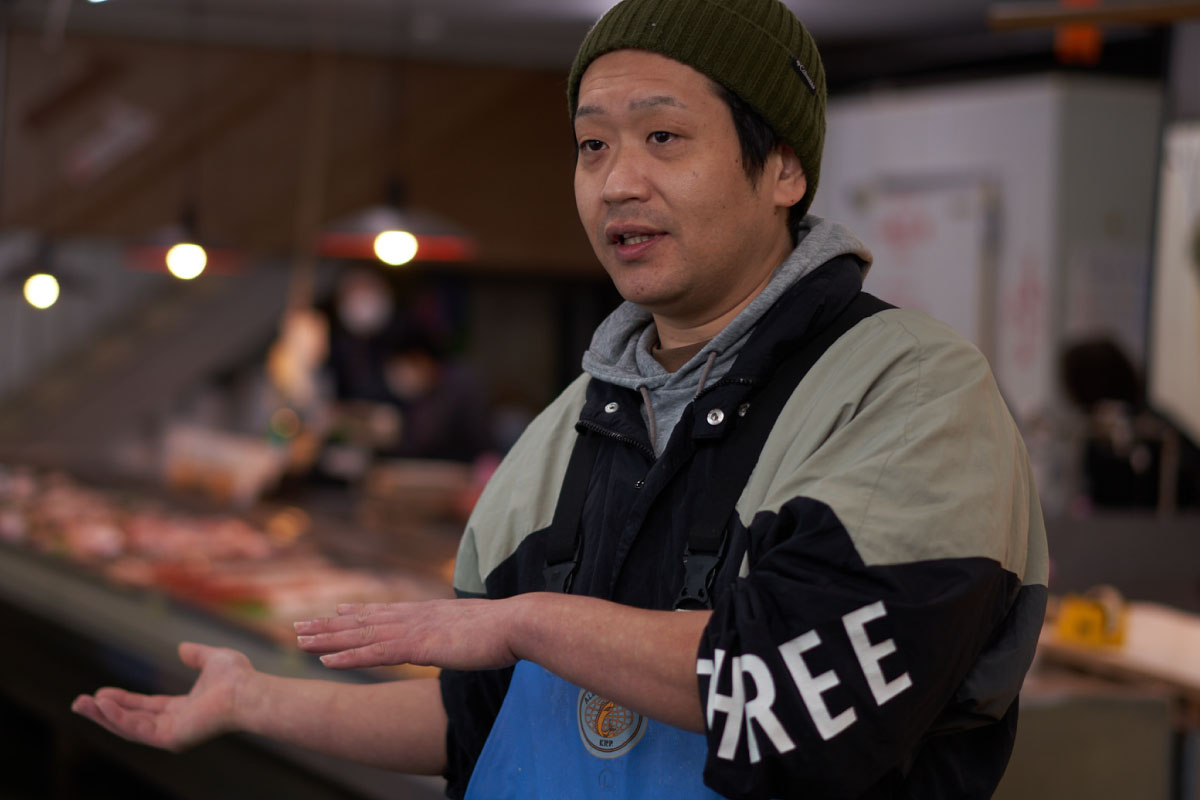 Mr. Yuya talks in his fish store about the life of fishermen and the different seasonal seafood
